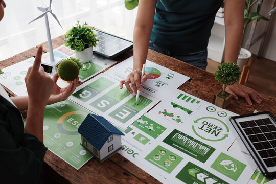 Engineers analyzing charts and discussing eco-friendly building project for sustainable development - Powered by Adobe