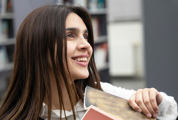 Smiling woman holding books in a library