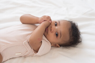 Top view of newborn baby in diaper lying on white blanket on bed. Healthy African American newborn...