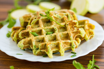 Waffles with green onions, zucchini and spices on a wooden table