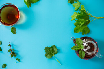 Green tea with currant leaves and mint in glass teapot and cup