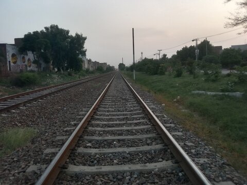 Railway Tracks Leading into the Distance under a Cloudy Sky