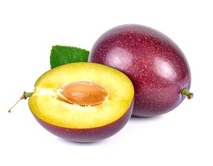 Fresh plums sliced open showing pit on a white surface