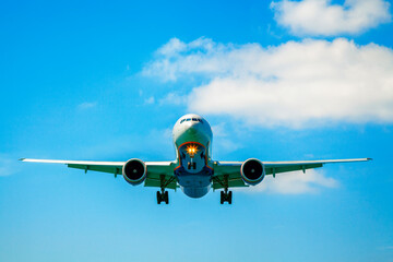 Passenger airplane flying in the sky. Travel background with airplane flying in the blue sky. View directly in front. Passenger airplane landing.