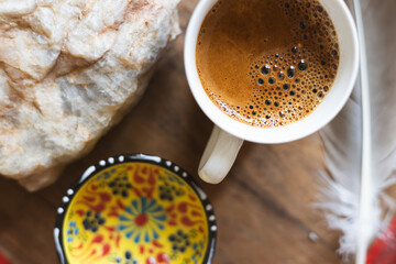 Warm cup of coffee on a wooden table with decorative bowl and natural stone elements in a cozy...