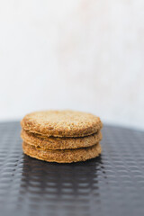Freshly baked cookies stacked neatly on a black textured surface ready to be enjoyed with a cup of tea or coffee