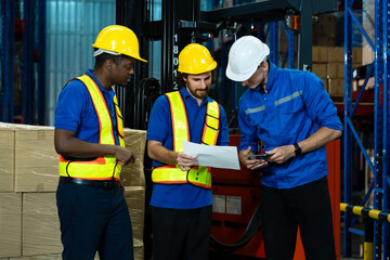 Caucasian supervisor holding tablet talking with african and caucasian warehouse workers holding checklist near forklift and stacked boxes in storage area with teamwork and task planning concept