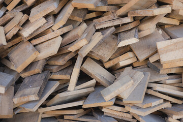 Stacked wooden planks in a storage area with natural lighting showcasing various shapes and sizes