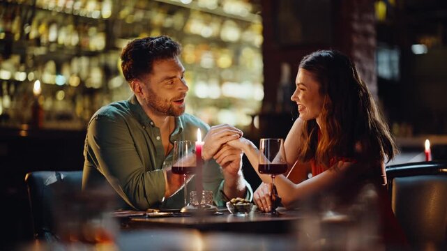 Loving boyfriend talking girlfriend holding hands in luxury night club closeup.