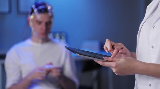 Man wearing EEG topographer for examining brain, doctor making electrogram of scalp activity. Researching of brain work using electroencephalography headset.