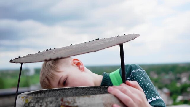 A guy walking on the roof of a high-rise building looks into the ventilation pipe. The teenager decided to retire to the roof
