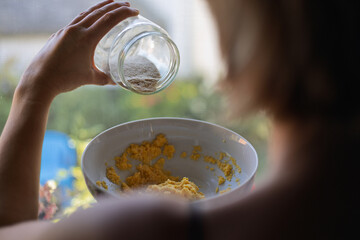 Woman preparing dough at home in a sunlit kitchen during the day, showcasing a process of baking...