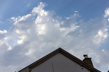 Cloudy sky view above a residential roof during late afternoon in a serene neighborhood