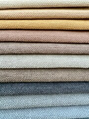 A vibrant display of colourful fabric pieces like towels stacked neatly on top of each other. Represents textile variety, fashion materials, and creative design resources.