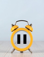 A small yellow alarm clock with pause symbol