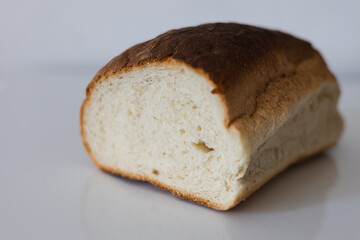 Freshly baked loaf of bread resting on a clean surface with a golden crust and soft interior, perfect for sandwiches or breakfast