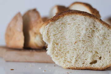 Freshly baked bread loaf displayed on a wooden board, showcasing its soft interior and golden...