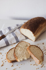 Freshly baked whole grain bread laid out on a table with sliced pieces, knife, and cloth napkin at morning light