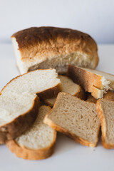 Freshly baked loaf of bread with slices arranged on a white surface, showcasing different textures and colors, perfect for meal preparation or sharing at a gathering