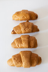 Freshly baked croissants arranged neatly on a white surface showcasing their golden-brown hues and flaky layers in a cozy kitchen setting