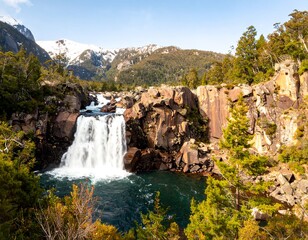 Scenic waterfall cascading into a rocky pool, surrounded by lush greenery and mountains