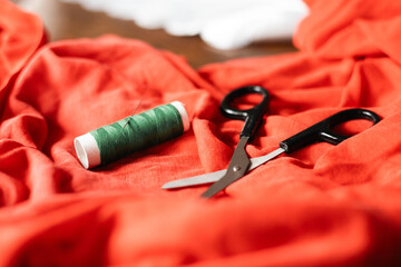 Crafting with vibrant orange fabric, green thread, and sharp scissors in a cozy workspace