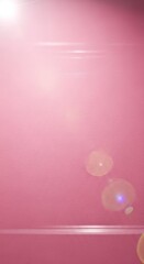 A soft, muted pink surface with subtle light flares and a horizontal highlight.