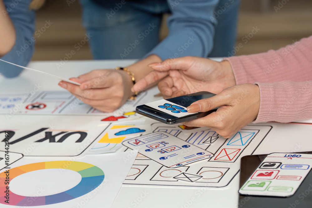 Aufkleber ux and ui design team collaborating with sketches and smartphone