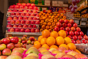 Vibrant Fruit Stall Displaying Oranges, Apples, and Grapes in Local Market.