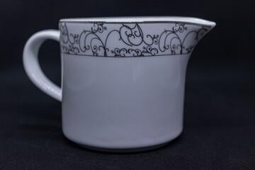 White porcelain creamer with delicate black floral patterns.