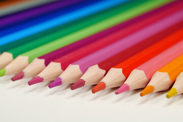 New wooden colored pencils of rainbow colors, perfectly sharpened, lie on table