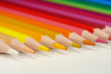 New wooden colored pencils of rainbow colors, perfectly sharpened, lie on table
