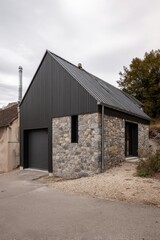 Modern stone and metal house located in a quiet rural area surrounded by nature, featuring a sloping roof and large windows that invite natural light