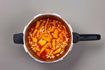 A classic Brazilian dish known as dobradinha, prepared with beef tripe, white beans, and tropical spices, served with traditional farofa made from toasted cassava flour.