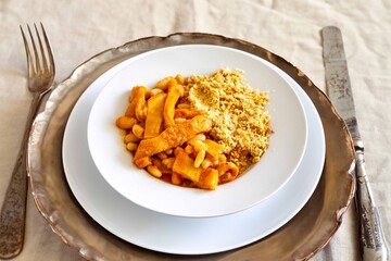 A classic Brazilian dish known as dobradinha, prepared with beef tripe, white beans, and tropical spices, served with traditional farofa made from toasted cassava flour.