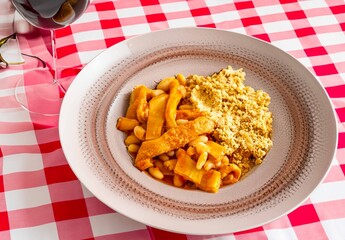 A classic Brazilian dish known as dobradinha, prepared with beef tripe, white beans, and tropical spices, served with traditional farofa made from toasted cassava flour.
