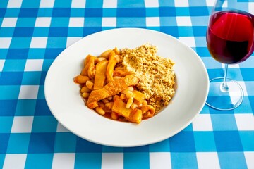 A classic Brazilian dish known as dobradinha, prepared with beef tripe, white beans, and tropical spices, served with traditional farofa made from toasted cassava flour.