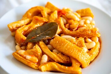 A classic Brazilian dish known as dobradinha, prepared with beef tripe, white beans, and tropical spices, served with traditional farofa made from toasted cassava flour.