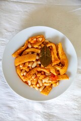A classic Brazilian dish known as dobradinha, prepared with beef tripe, white beans, and tropical spices, served with traditional farofa made from toasted cassava flour.