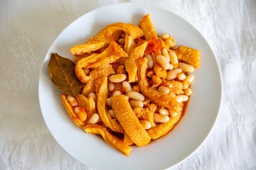 A classic Brazilian dish known as dobradinha, prepared with beef tripe, white beans, and tropical spices, served with traditional farofa made from toasted cassava flour.