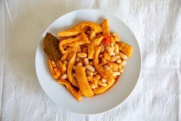 A classic Brazilian dish known as dobradinha, prepared with beef tripe, white beans, and tropical spices, served with traditional farofa made from toasted cassava flour.