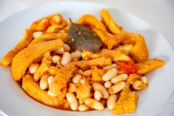 A classic Brazilian dish known as dobradinha, prepared with beef tripe, white beans, and tropical spices, served with traditional farofa made from toasted cassava flour.