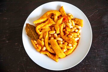 A classic Brazilian dish known as dobradinha, prepared with beef tripe, white beans, and tropical spices, served with traditional farofa made from toasted cassava flour.
