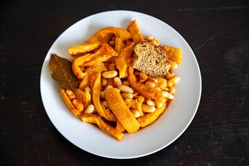 A classic Brazilian dish known as dobradinha, prepared with beef tripe, white beans, and tropical spices, served with traditional farofa made from toasted cassava flour.