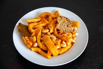 A classic Brazilian dish known as dobradinha, prepared with beef tripe, white beans, and tropical spices, served with traditional farofa made from toasted cassava flour.