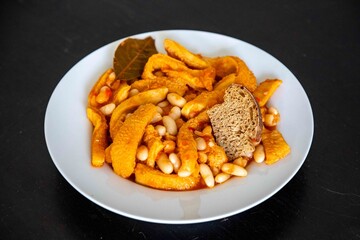 A classic Brazilian dish known as dobradinha, prepared with beef tripe, white beans, and tropical spices, served with traditional farofa made from toasted cassava flour.