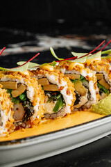 Close-up of sushi rolls combining salmon, mango, cucumber, and cream cheese inside rice and nori. Topped with thin salmon slices 