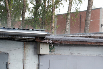 It's raining heavily in the city. Raindrops are falling on the roof of a building.