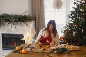 Joyful family making gingerbread christmas cookies on table with dough and metal cutters against...