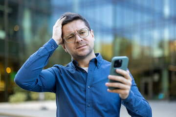 Man experiencing business-related challenge while holding smartphone outdoors